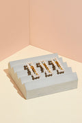 Three of The Hair Edit's Pearl Square Gold Jeweled Clip Hair Accessories in a row on cement block display